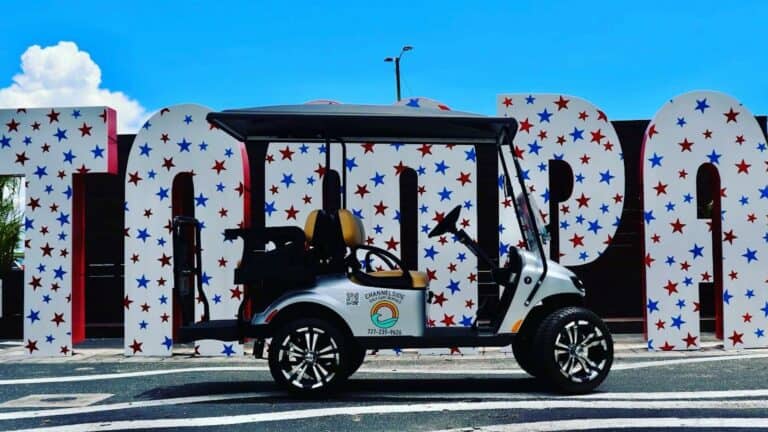 golf cart parked in front of a large Tampa sign covered in stars and sparkles