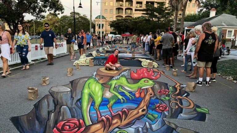 A 3D chalk painting featuring a gecko/chicken monster. It's bright green. Spectators watching from behind barriers.