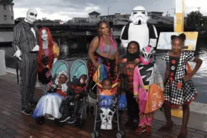 A family dressed in Disney and Star Wars costume pose on a Riverwalk at sunset