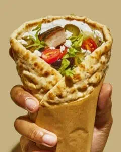 a large pita wrap filled with eggplant dip, chicken and veggies.