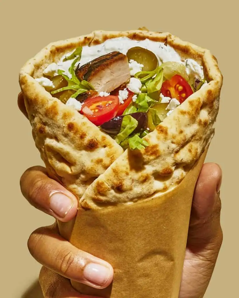 a large pita wrap filled with eggplant dip, chicken and veggies. 