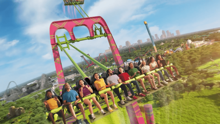A giant swing with purple seats and light green arms soars in the air.