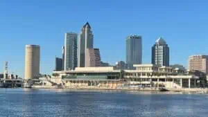 Skyline view of downtown Tampa on the waterfront. A dock for a large ferry is visible in front of a large convention center