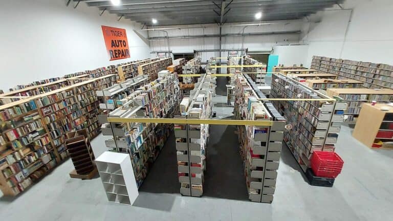 A warehouse full of used books. 6 rows of shelves are arranged inside a big warehouse.