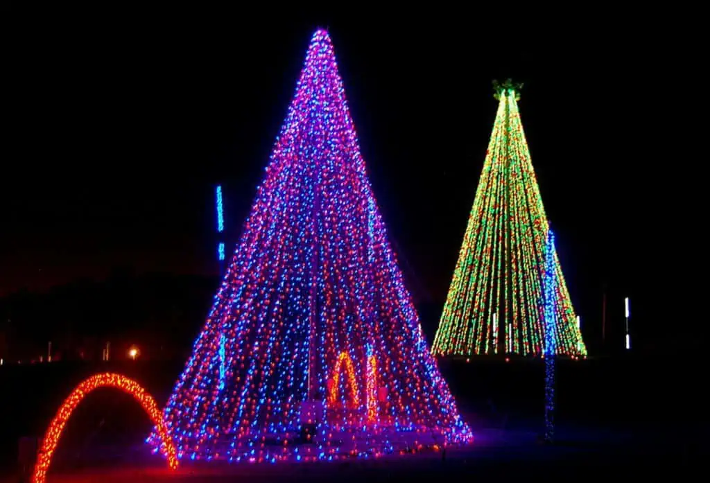 Two large light displays formed into the shape of trees. The tree in front is read and blue. The tree in the back is green, yellow, and red. 