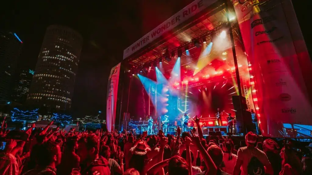 a huge concert in the park. Red lights shine on the waterfront stage