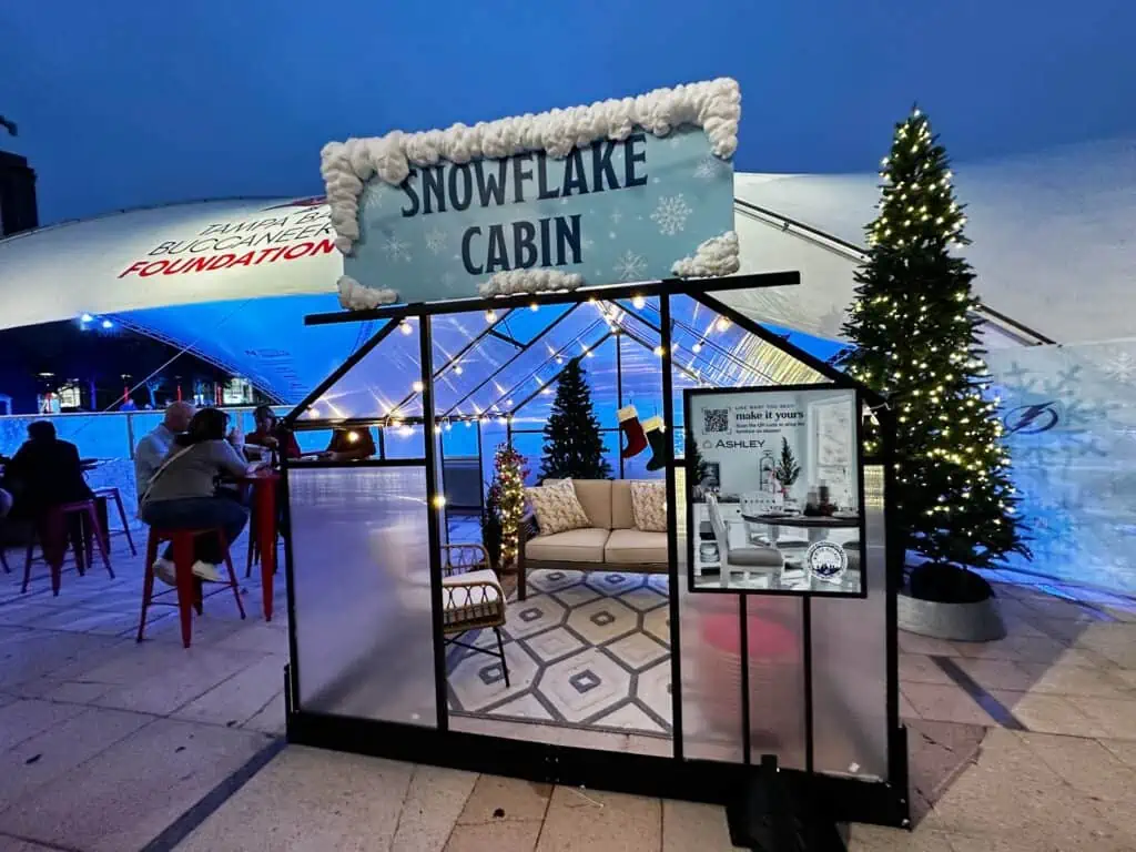 a small cabin filled with furniture next to an ice rink at a park