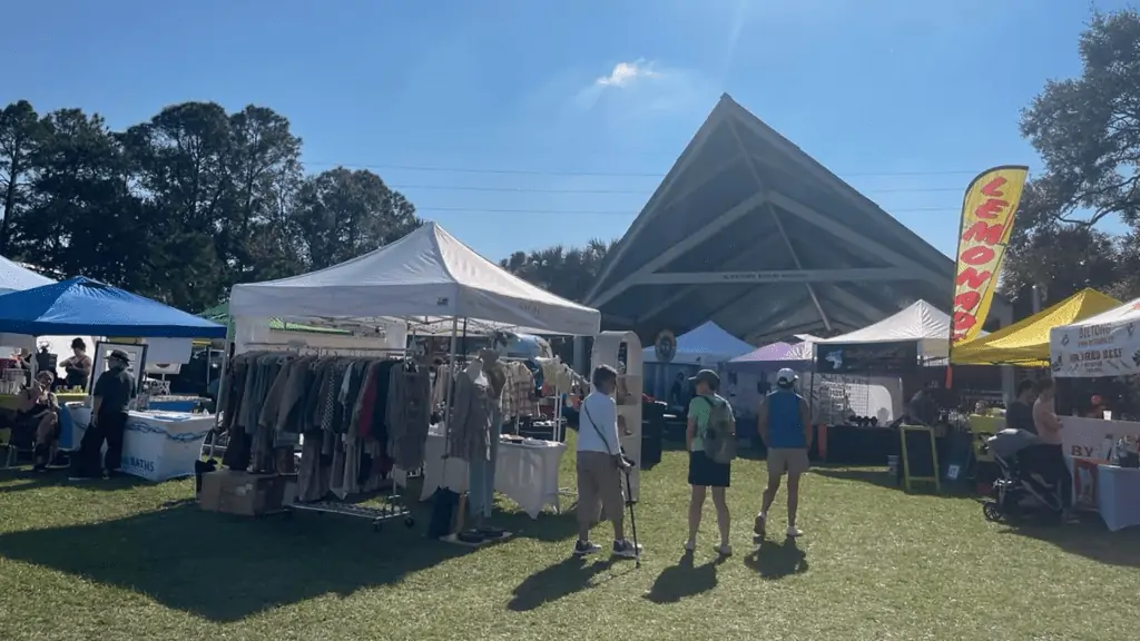 Vendor tends set up in front of a band stand in a park.