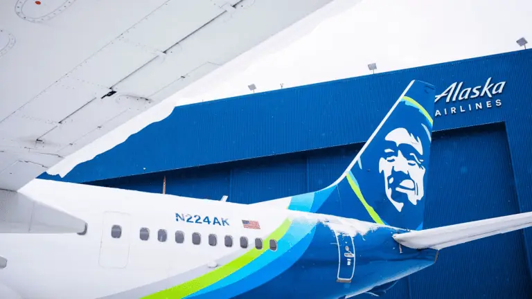 Exterior of a plane fin with a blue-green paint job. The plane is parked in a hangar.