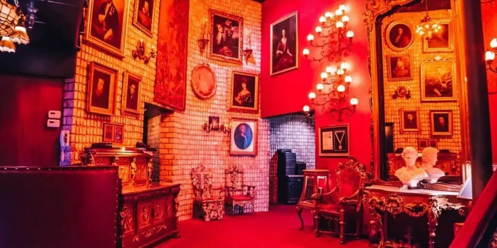 A large lounge area with candles on the wall. Historic pantings scale the wall and a small bust sits in front of a tall mirror. 