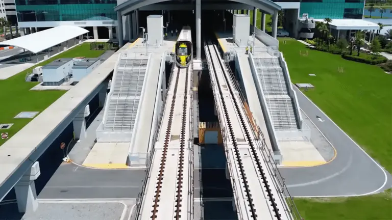 A train leaves an elevated station at an airport.