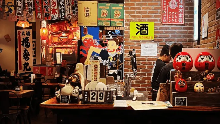 Inside a sushi restaurant. Exposed brick walls, and colorful signs hang from the ceilings.