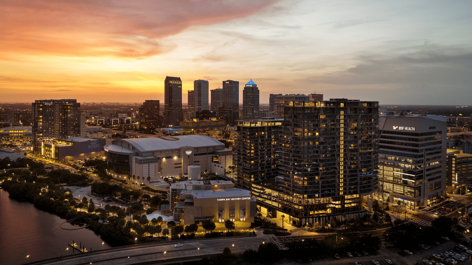 Aerial view of a major downtown area. Buildings are lit up on the waterfront.