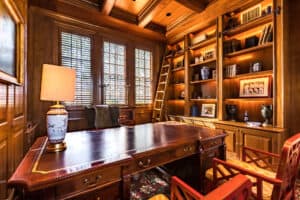 A large office with a large wooden desk, and a full library.