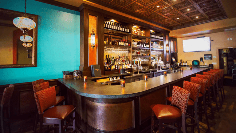 interior of a bar with teal walls, leather seats, and an l-shaped bar.