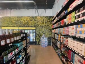 A black and yellow mural in the background. Shelves of wine bottles on the right, rows of tumblers on the left.
