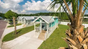 a tiny home at a large campsite in Florida. The house is painted teal with white trim.