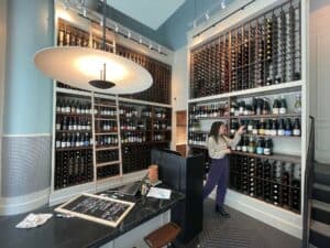 inside a curated wine shop. A ladder is hooked to the top shelf for customers to browse