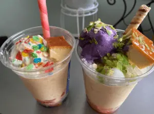 Two cups filled with condensed milk, shaved ice, flan, jellies and purple ube ice cream.