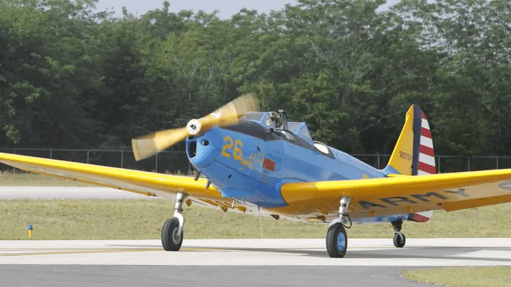 A blue and yellow prop plane taking flight on a runway