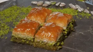 Honey covered baklava on a plate. 4 pieces are visible.