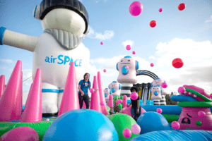 A giant bounce house with tall inflatable astronauts and huge bouncy balls flowing around.