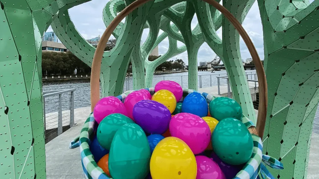 A bag of colorful Easter eggs held up on a riverwalk 