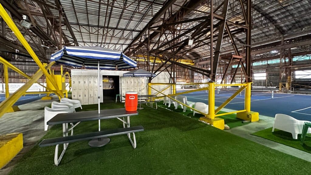 Picnic tables set up on green turf inside a warehouse.