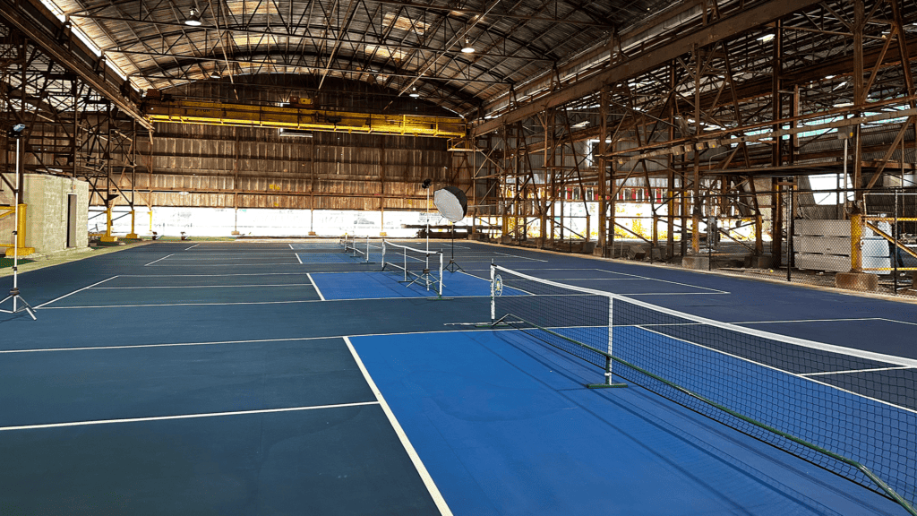 indoor pickleball club with 4 blue courts visible inside a warehouse