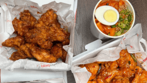 aerial view of two baskets of fried chicken, and a bowl of noodles topped with a hardboiled egg.