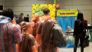 guests wearing ponchos line up for a slime machine.