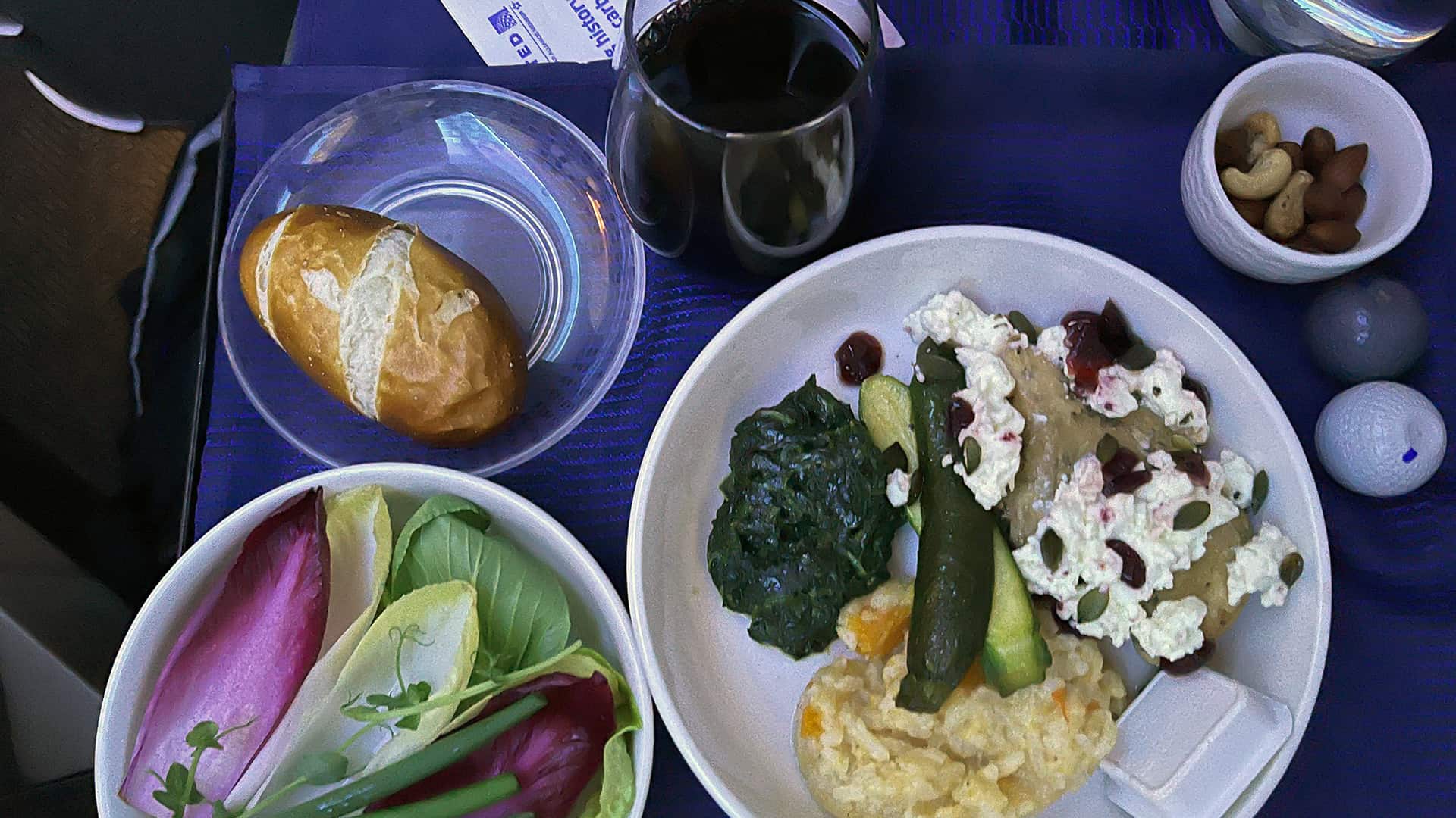 A full meal served on a business class flight on United Airlines which included a salad, bread and wine.
