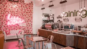 inside a juice bar There's a pink floral wall with a neon sign on it.