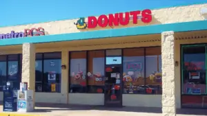 Exterior of a restaurant with a large red donuts sign over the front door.