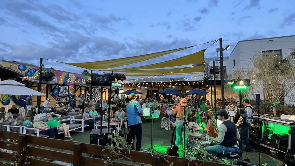 a band performs in a big beer garden at night.