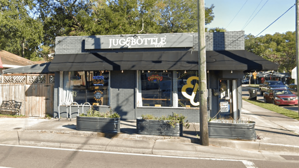 exterior of a small bottle shop with a black awning. Bike parking is visible to the left of the front door.