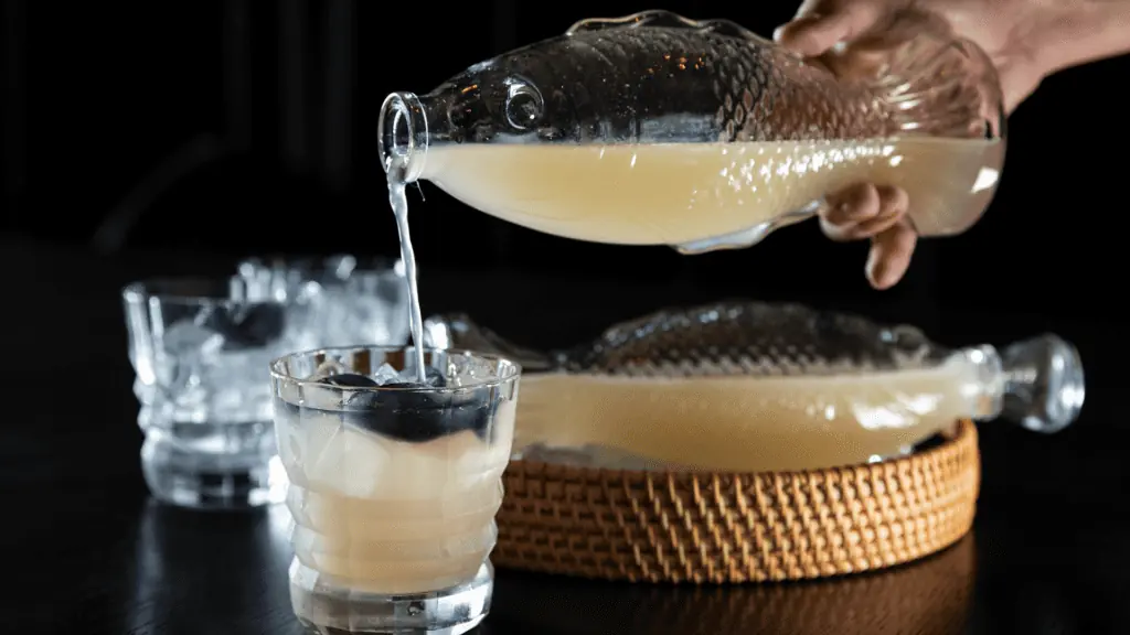 a cocktail being poured from a fish-shaped glass