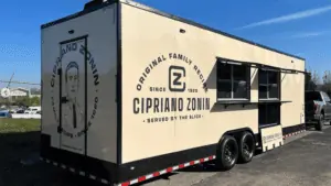 a food truck with a beige paint job and an open order window.