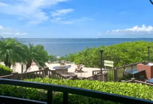 balcony view of a waterfront restaurant. Tables can be seen on a patio overlooking the gulf.