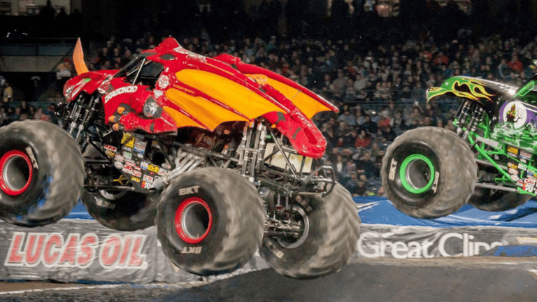 Two Monster Trucks riding on a dirt track