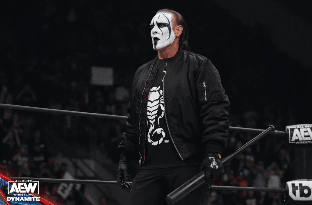 a man in black and white face paint holds a bat inside a wrestling ring