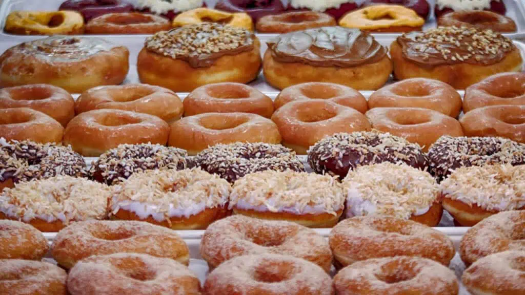 a big display of donuts behind a glass case 