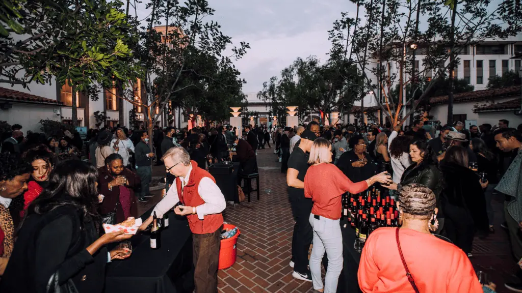 people gathered at tables enjoying different glasses of wine. This is an open air venue.