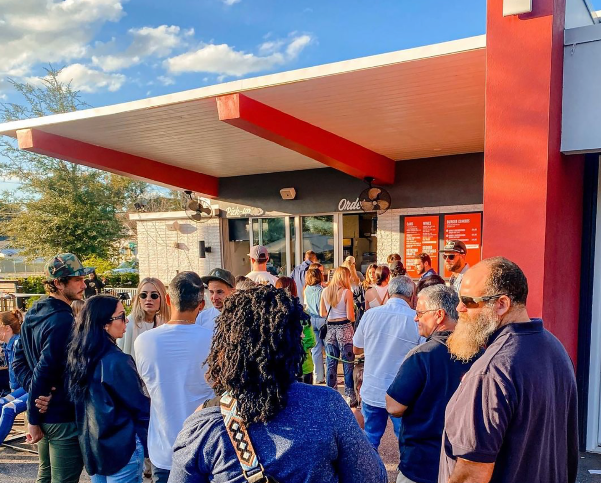 people line up outside a small burger order window