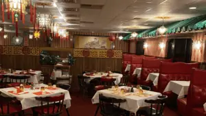 interior of a restaurant with red walls and circular tables covered in white linen cloths.