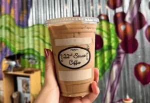 Iced coffee drink held up in front of a mural covered wall