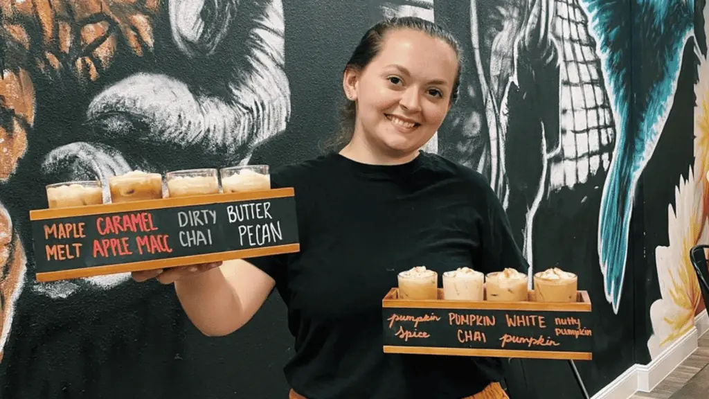 two flights of different coffee flavors held in each hand by a barista