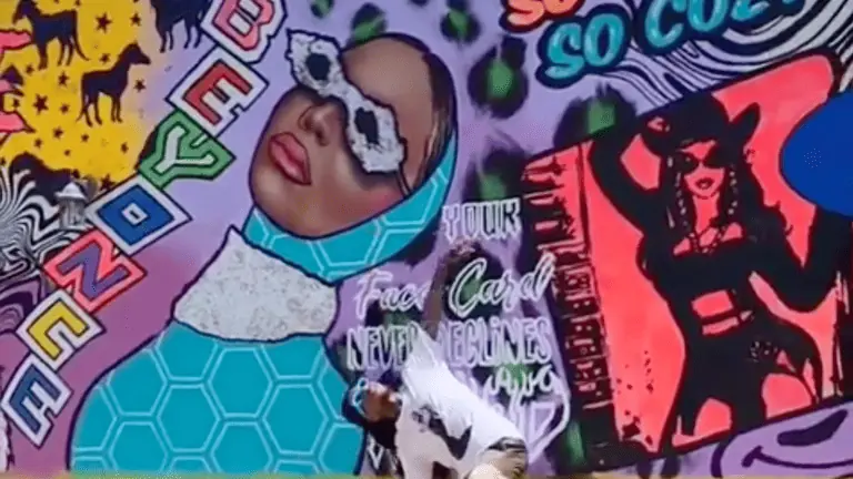 Artist in front of a Beyoncé mural.