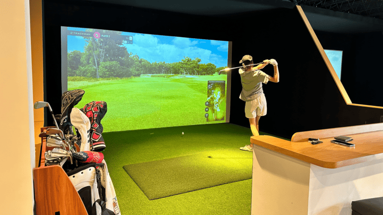 a golfer finishes his swing at a virtual golf lounge