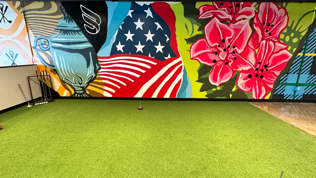 a putting green with a colorful mural behind it
